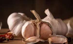 Czosnek na pryszcze, ząbki czosnku i suszone papryczki chili na drewnianym blacie. Naturalne sposoby na piękno.