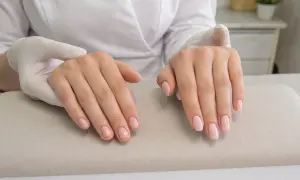 Dłonie po zabiegu manicure, z delikatnym, różowym lakierem na paznokciach. To właśnie jest manicure co to znaczy dbałość o dłonie.