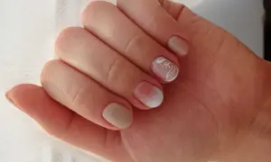 Delikatne rodzaje manicure: beżowe paznokcie z subtelnym zdobieniem białym wzorem na jednym paznokciu.