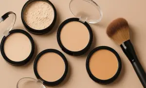 Kilka odcieni pudru, w tym sypki i prasowany, obok pędzla do makijażu. Idealny zestaw do perfekcyjnego wykończenia makijażu, jak z palety Kat Von D.