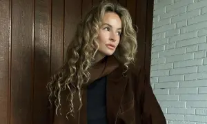 Kobieta z kręconymi blond włosami w brązowej marynarce. Kolor marynarki przypomina mi miód, taki **honey beige jaki to kolor** – ciepły i przytulny.