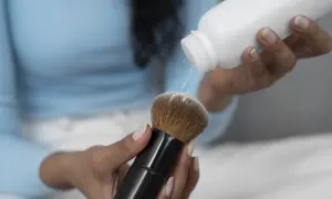 Kobieta sypie puder na pędzel do makijażu. To jeden ze sposobów, jak wyczyścić pędzle do makijażu, aby były jak nowe.