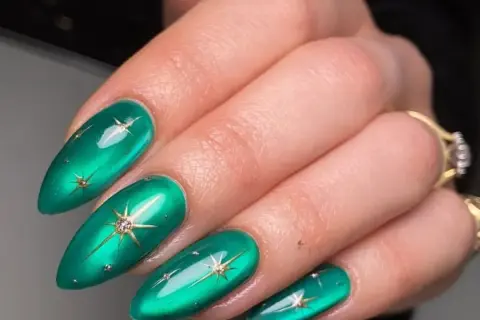 Paznokcie miętowe z białym brokatem i złotymi gwiazdkami. Wyglądają jak nocne niebo pełne gwiazd.