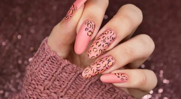 Długie, matowe paznokcie w kolorze brzoskwiniowym z motywem panterki. Wzory panterki są w odcieniach czerni i pomarańczu, tworząc efektowny manicure.