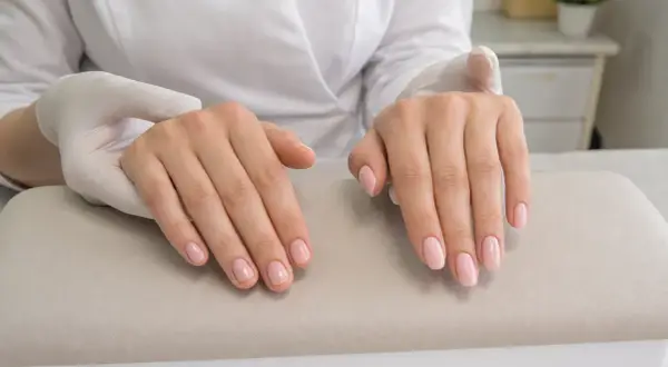 Dłonie po zabiegu manicure, z delikatnym, różowym lakierem na paznokciach. To właśnie jest manicure co to znaczy dbałość o dłonie.
