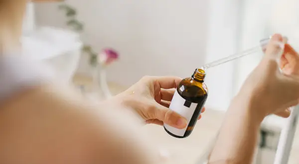 Kobieta aplikuje serum z niacynamidem na dłoń. Bezpieczny wybór dla skóry w ciąży.