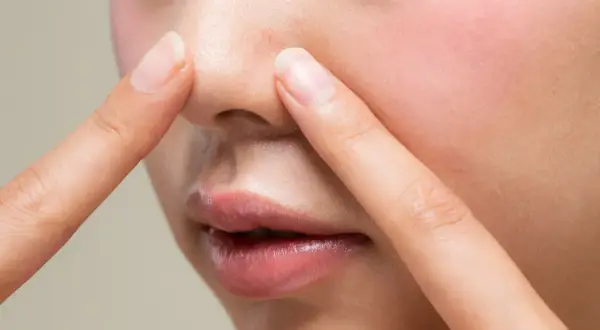 Dłonie dotykają nosa, ukazując pory i zaczerwienienie. Czy to sebum? Dowiedz się, co to jest i jak sobie z nim radzić.