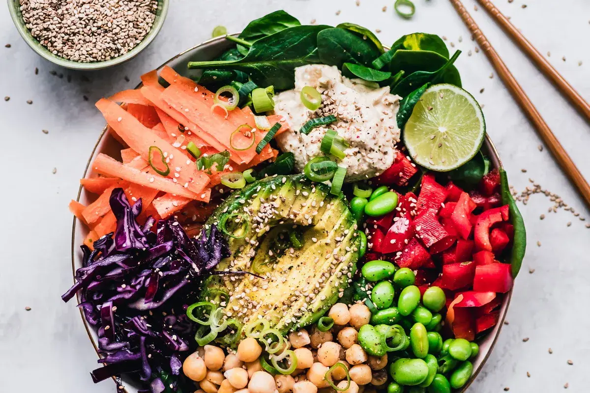 Kolorowa miska pełna warzyw: marchewka, awokado, czerwona kapusta, papryka, edamame, ciecierzyca i szpinak. To idealny posiłek dla nawilżenie skóry od środka.