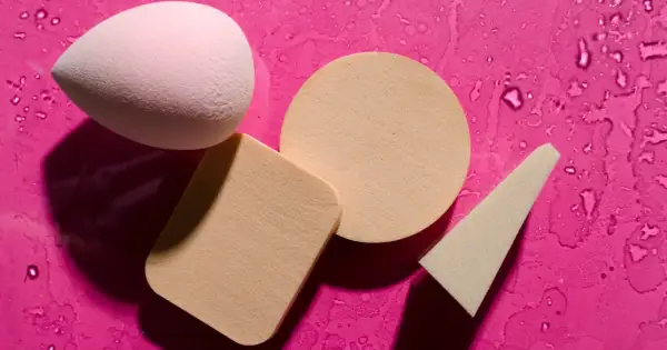 Różowy i beżowy beauty blender oraz gąbeczki na mokrym, fuksjowym tle. Dowiedz się, jak wyczyścić beauty blender, by służył Ci dłużej.