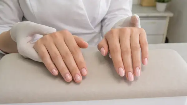 Dłonie po zabiegu manicure, z delikatnym, różowym lakierem na paznokciach. To właśnie jest manicure co to znaczy dbałość o dłonie.